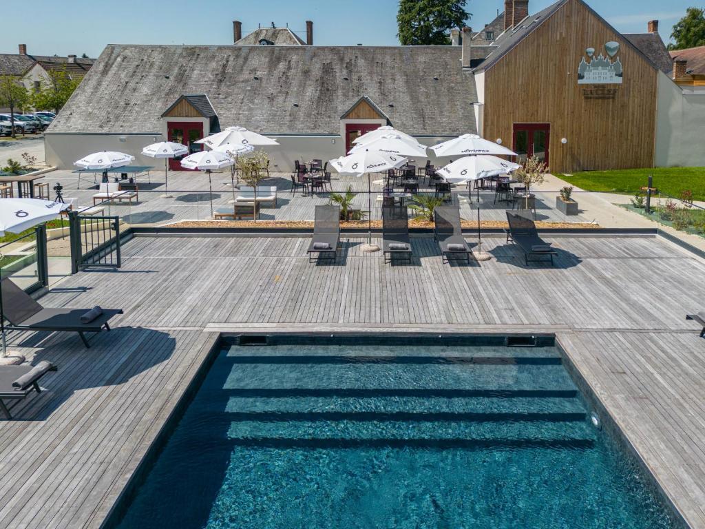 马斯利维La Clef des Châteaux的一个带遮阳伞和桌椅的游泳池