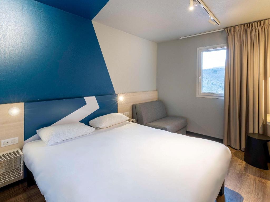米洛ibis Budget Millau Viaduc的卧室配有白色的床和蓝色的墙壁