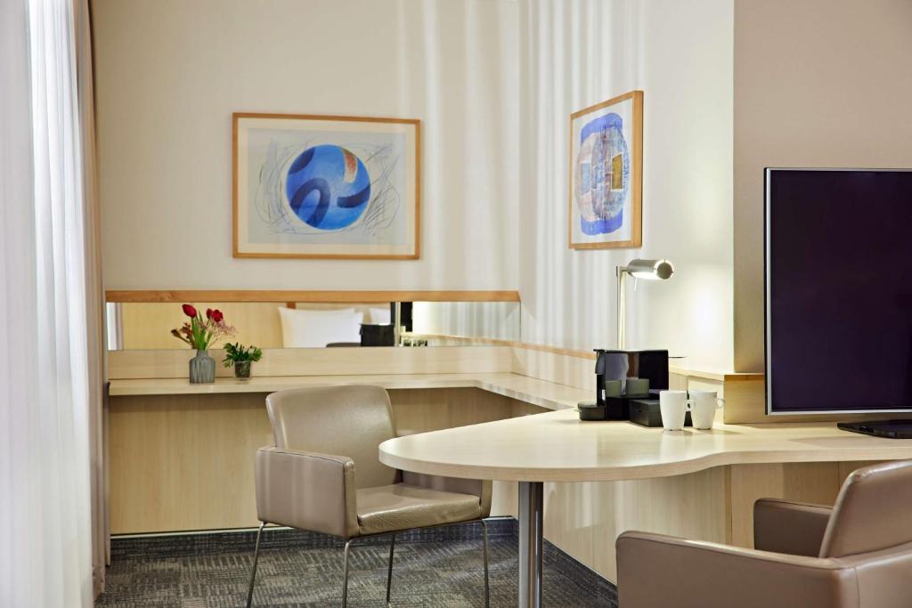 科隆Lindner Hotel Cologne Am Dom, part of JdV by Hyatt的酒店客房设有一张带显示器和椅子的书桌
