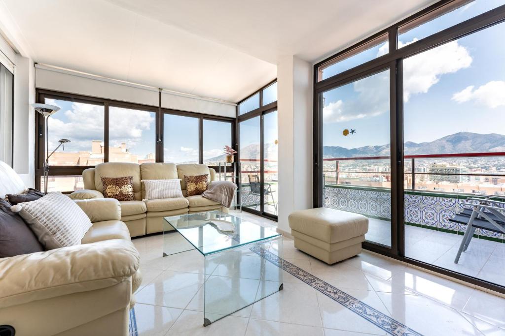 福恩吉罗拉MalagaSuite Skyviews Fuengirola的带沙发和玻璃桌的客厅