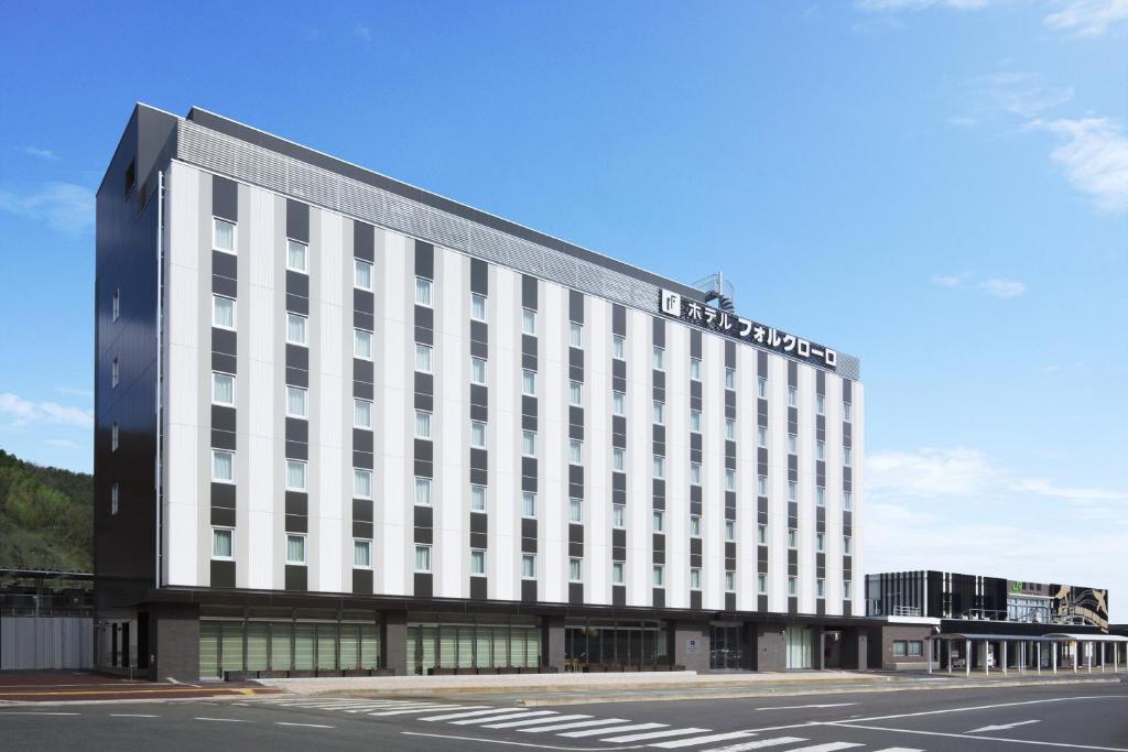 釜石福尔克罗三里库酒店的一座大型白色酒店大楼,设有停车场