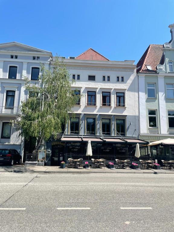 吕贝克荷尔斯登托菲林沃尔姆艮酒店的街道边的一座带桌子和遮阳伞的建筑