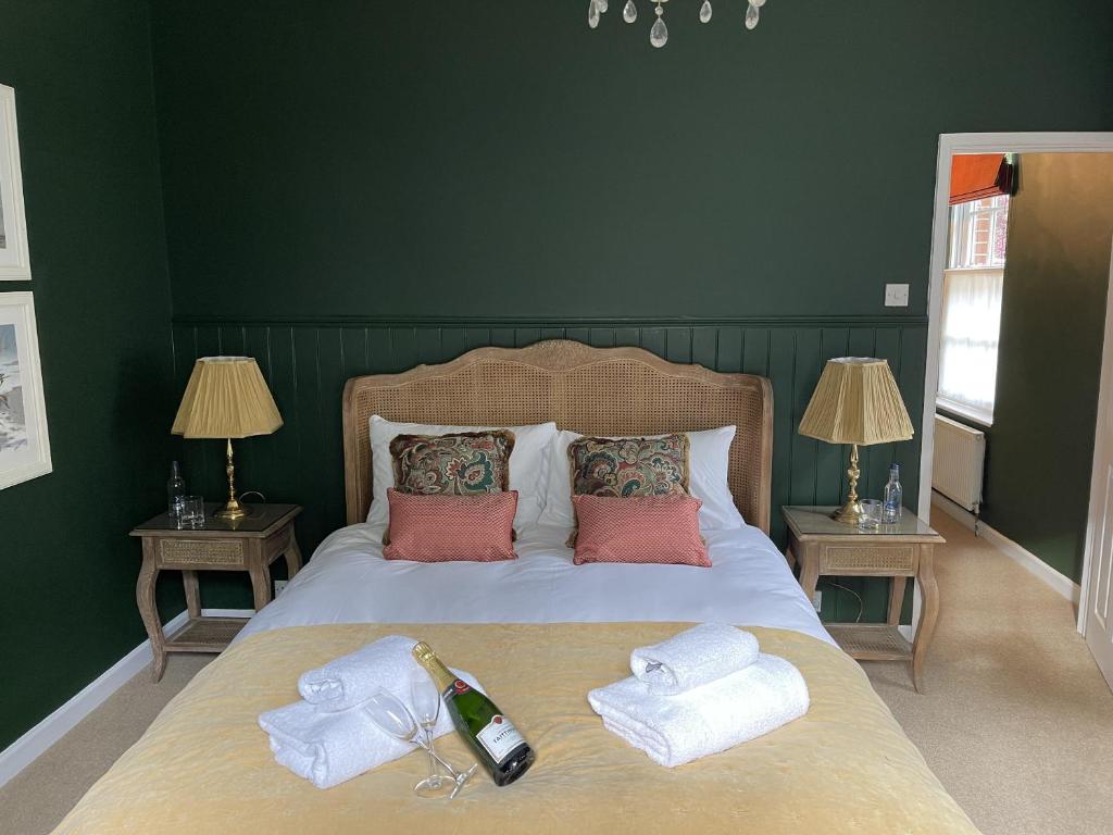 诺里奇The Lodge at Salhouse的一张带两条毛巾的床和一瓶葡萄酒