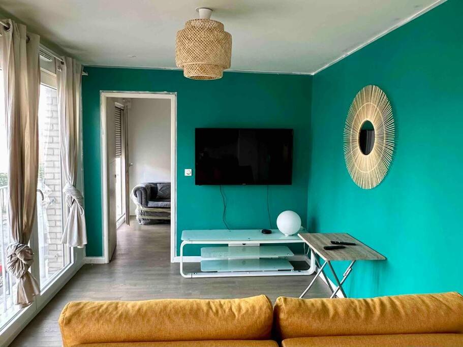 庞坦Loue super appartement standing的客厅配有沙发和蓝色墙壁上的电视