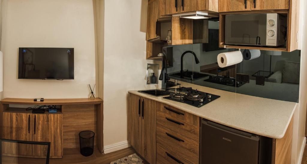 阿布贾C. Apartments Annex的一间带炉灶的厨房和一台墙上的电视