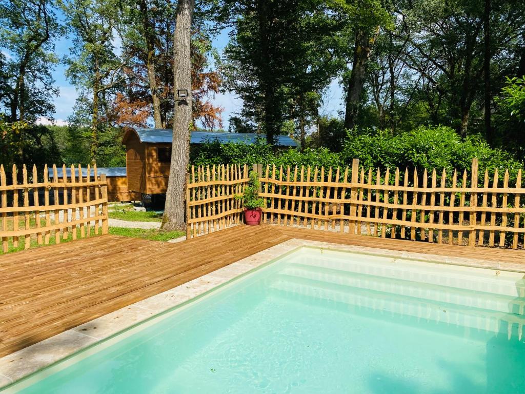 胡菲涅克Les Roulottes de l Herm Piscine Jacuzzi Perigord的后院的游泳池,带有木栅栏