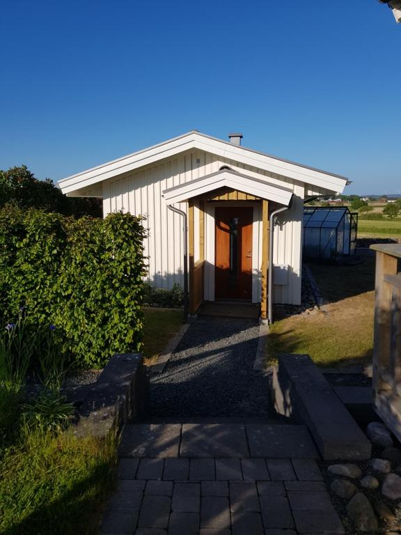 TrÃ¤slÃ¶vslÃ¤geStuga i Gamla-köpstad的一座白色的小建筑,在田野上有一扇门