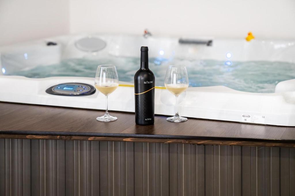 GonnosfanàdigaL'OLEANDRO Room's - Suite & Spa da Giuseppe的浴缸内的一瓶葡萄酒和两杯酒
