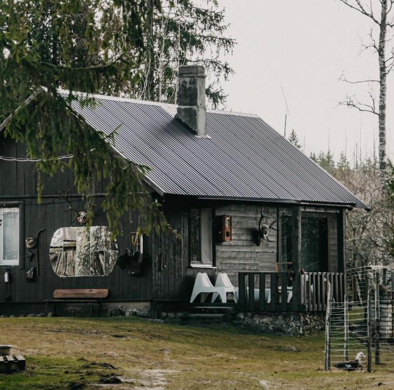 塔尔西Private Farm Jakuzzi Sauna in the forest的黑色屋顶和门廊的房子