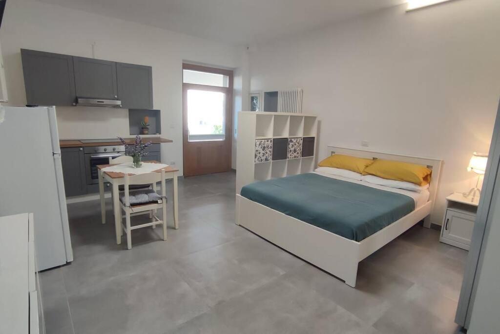 圣萨尔沃44 gatti Grazioso monolocale的一间卧室配有一张床铺和一张桌子,还设有一间厨房