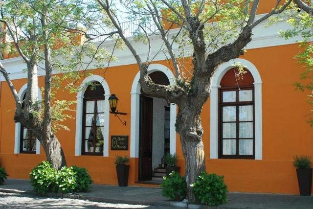 科洛尼亚-德尔萨克拉门托拉米圣酒店的一座橘色的建筑,前面有两棵树