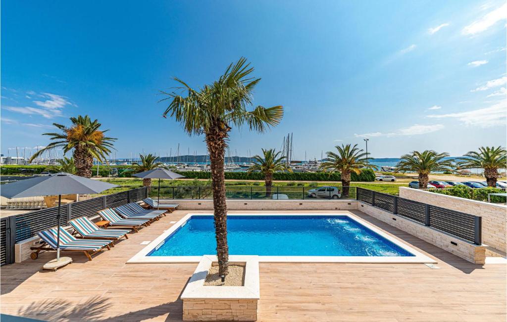 卡什泰拉Gorgeous Home In Kastel Gomilica With Wifi的一个带棕榈树和躺椅的游泳池