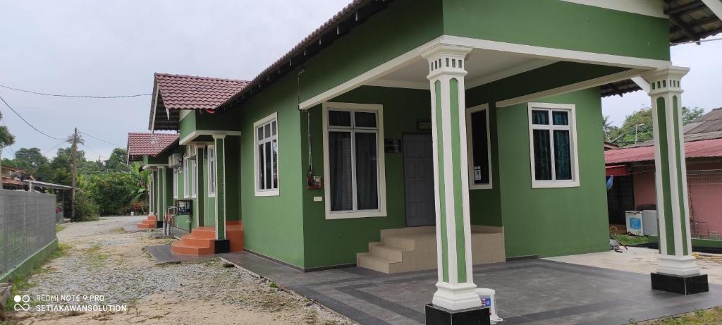 Kampong PauhHomestay Anjung Ismail Anjung Rahmah的街道上白色柱子的绿色房子