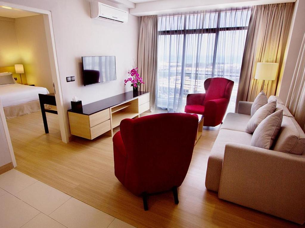 马六甲海峡套房酒店的酒店客房设有一间带沙发和椅子的客厅