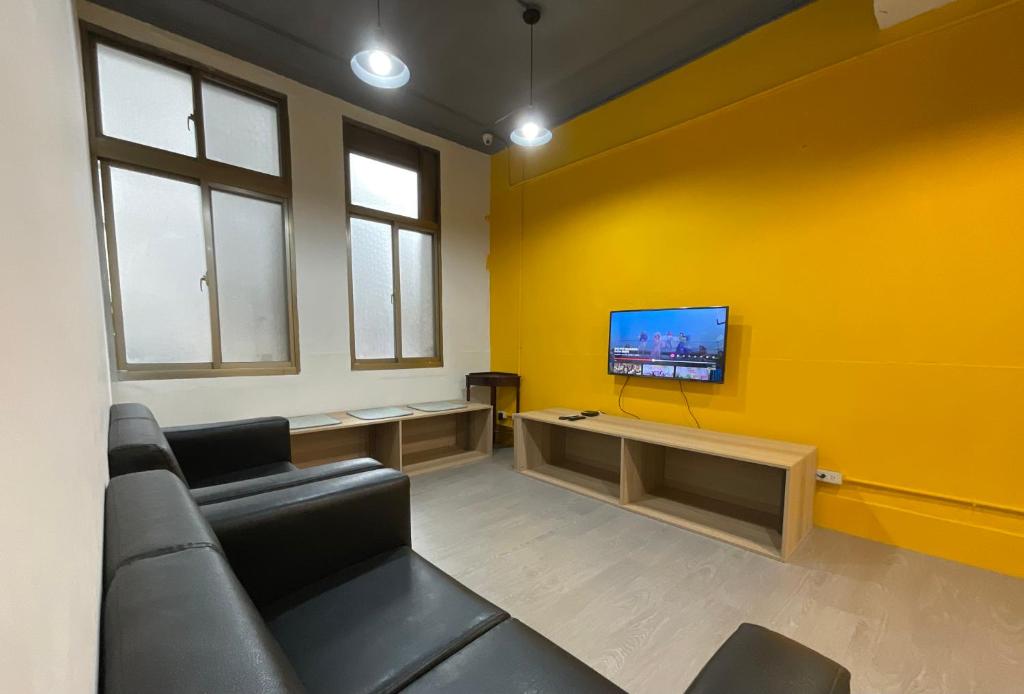 台北星空间 Star co-living space的带沙发的客厅和黄色墙壁上的电视