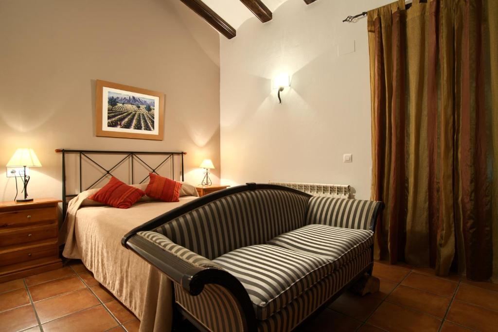 GúdarCasa Rural El Olmo的一间卧室配有一张沙发和椅子的床
