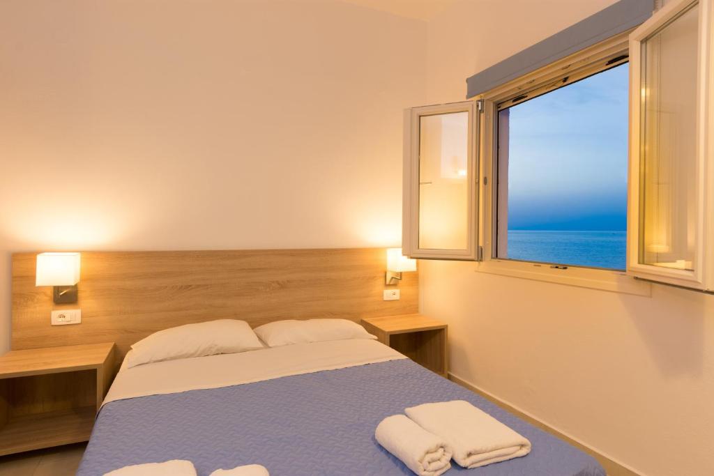 莫拉托斯Socrates Apartmens & Restaurant的一间卧室设有一张床和一个海景窗户