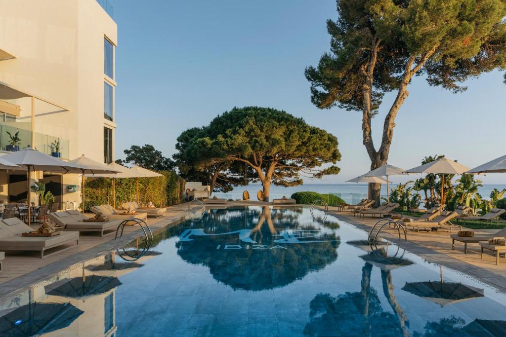 圣埃乌拉利亚ME Ibiza - The Leading Hotels of the World的度假村的游泳池,配有椅子和遮阳伞