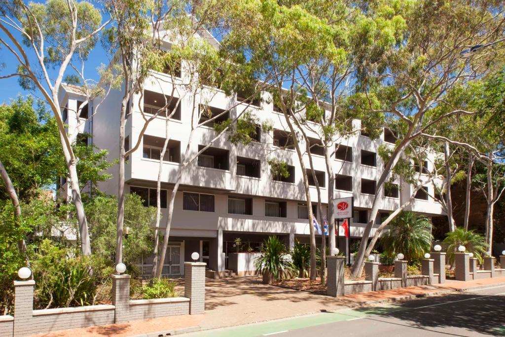 悉尼悉尼美罗阿斯皮尔酒店的前面有树木的白色建筑