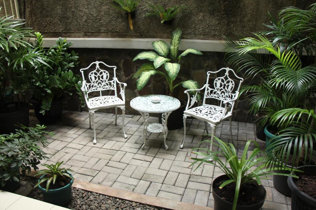 雅加达托芒住宿加早餐旅馆的庭院配有两把椅子和一张桌子,还有一些植物
