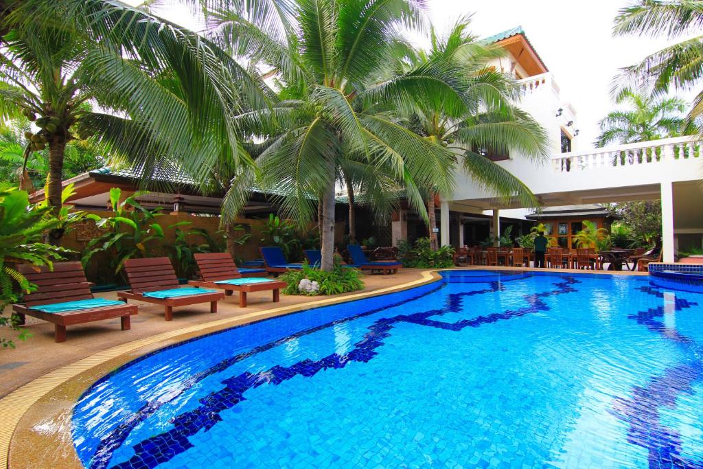 华欣华欣高尔夫别墅酒店的一座游泳池,旁边是椅子和棕榈树