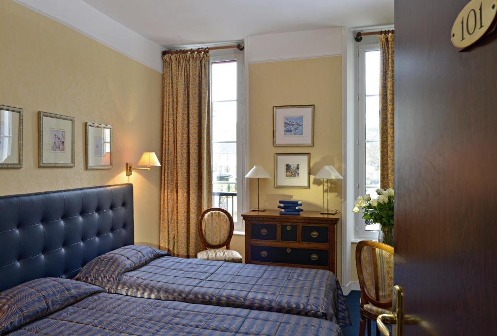 贝叶Churchill Hotel Bayeux Centre的一间卧室设有蓝色的床和窗户。