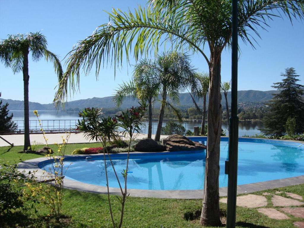 维拉卡洛斯帕兹casa con vista y bajada al lago的一座游泳池,旁边是一座湖泊,种有棕榈树