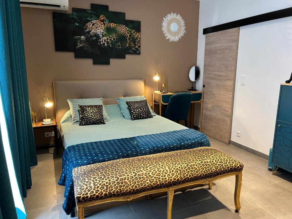 纳博讷La CORSA CHAMBRE FAMILIALE DELUXE的一间卧室配有一张带豹纹板凳的床