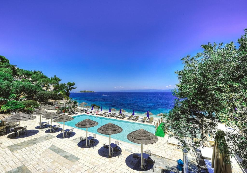 盖奥斯Agali Hotel Paxos的一个带遮阳伞和椅子的游泳池以及大海