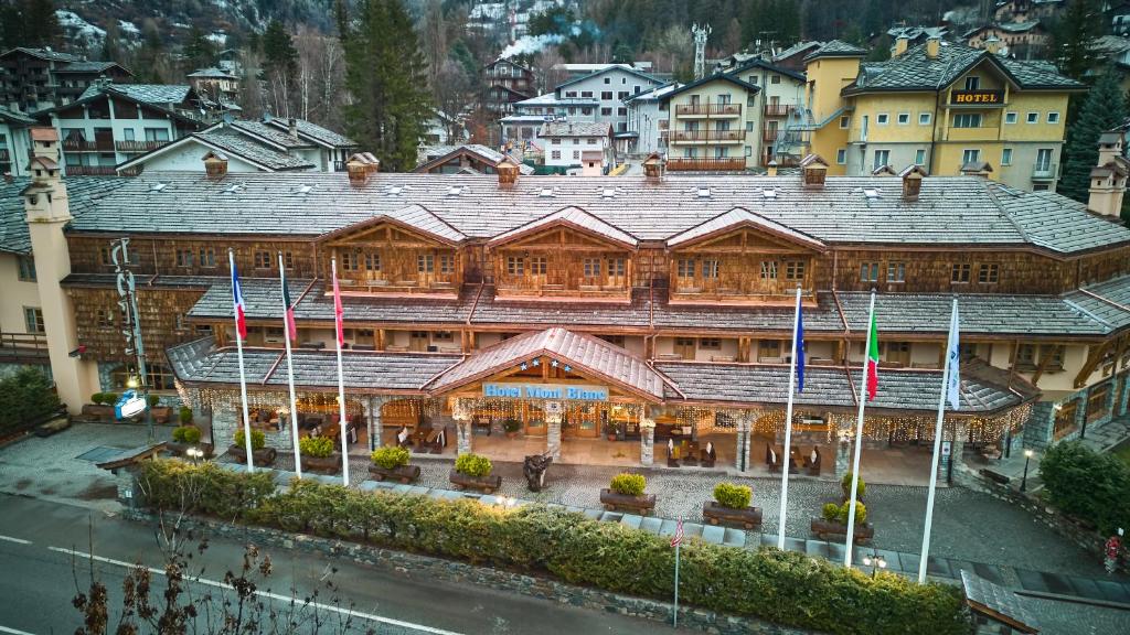 库马约尔iH Hotels Courmayeur Mont Blanc的前面有旗帜的大型木制建筑