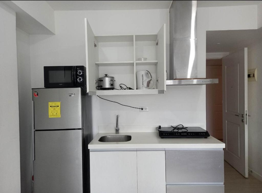 马尼拉SM Bicutan Rooms的白色的厨房配有冰箱和水槽