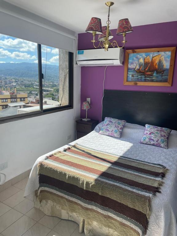 圣萨尔瓦多德朱APART HOTEL OFFICE céntrico的一间卧室配有一张紫色墙壁和窗户的床