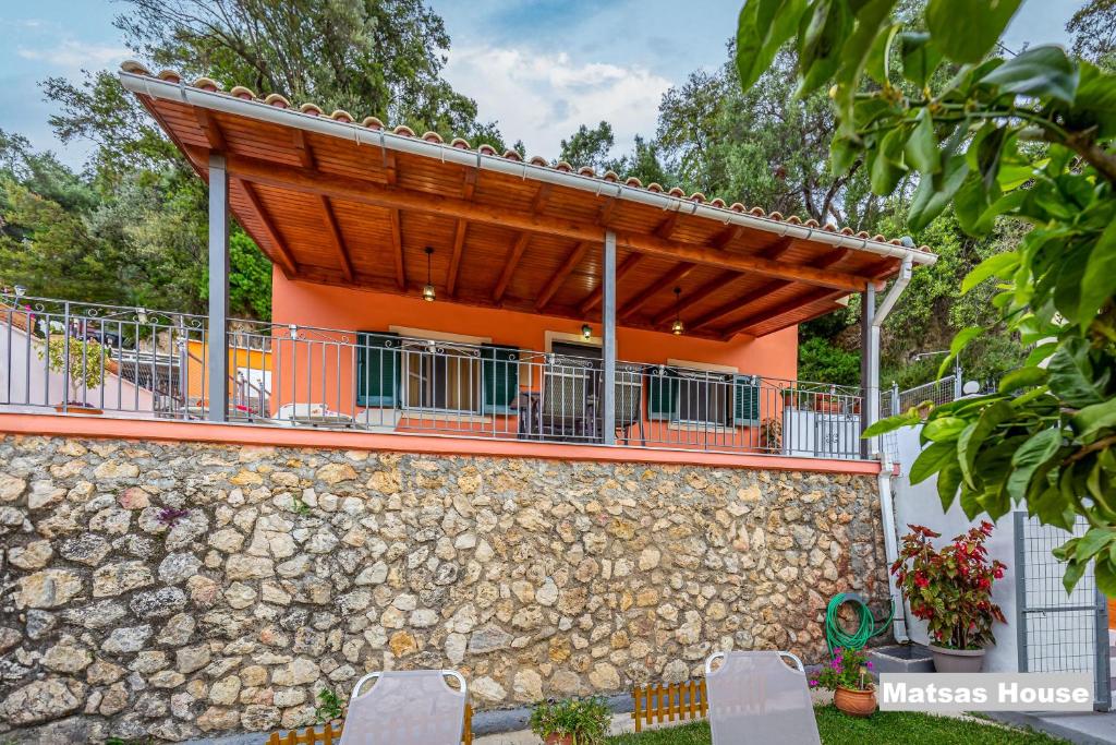 帕莱欧卡斯提撒Matsas House & Studio的一座橙色的房子,设有石墙和木屋顶