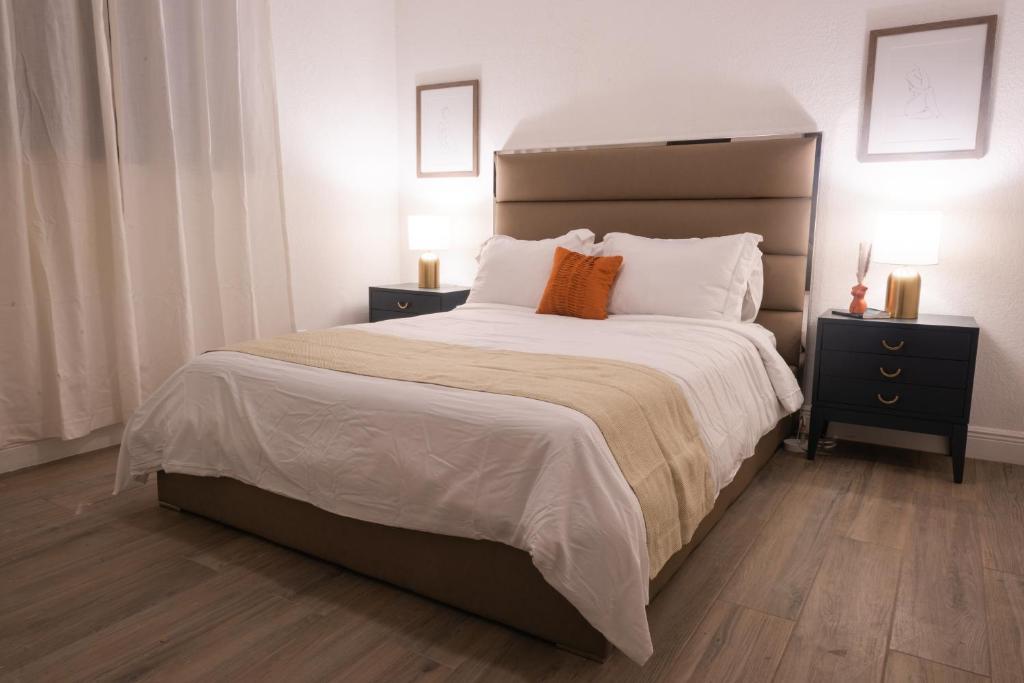 北迈阿密海滩New Star Suite Two的卧室配有一张带白色床单和橙色枕头的大床。