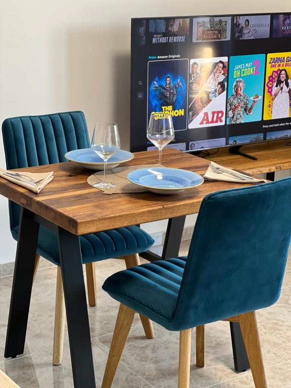 普莱克Apartment Summer Night的一张木桌,配有两杯酒杯和蓝色椅子