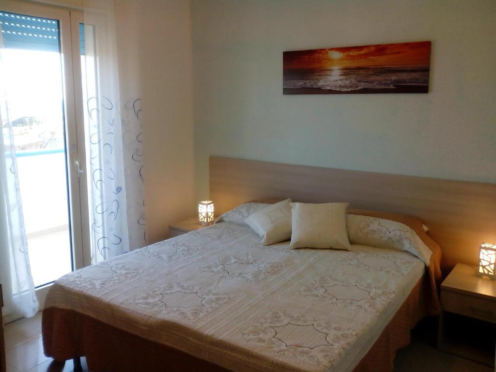 托里切拉B&B Trullo di Mare的一间卧室配有一张带两盏灯的床和一扇窗户。