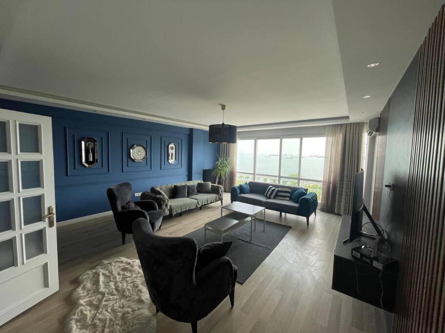 伊斯坦布尔Mükemmel Deniz Manzaralı Lüks的客厅拥有蓝色的墙壁,配有沙发和椅子