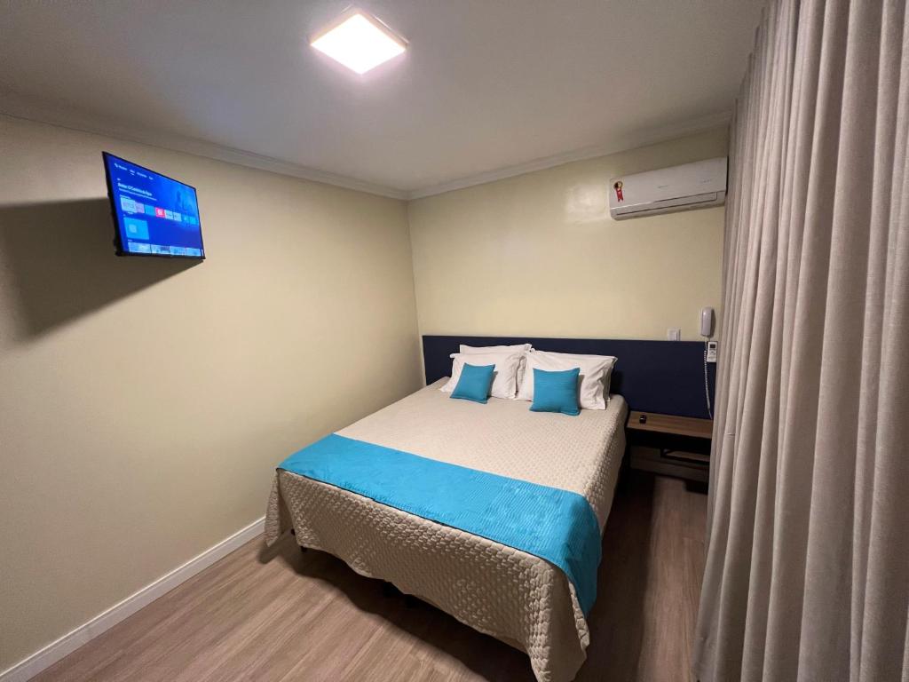 巴西利亚Hotel Suntuoso的卧室配有一张床铺,墙上配有电视