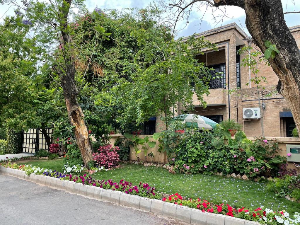 伊斯兰堡Riviera Courtyard Guest House Islamabad的一座房子前面有鲜花的花园