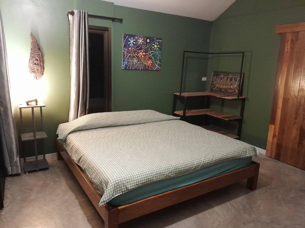 达叻府บ้านลูกจัน Bann Lookjan Trat的卧室设有一张位于绿色墙壁上的床铺