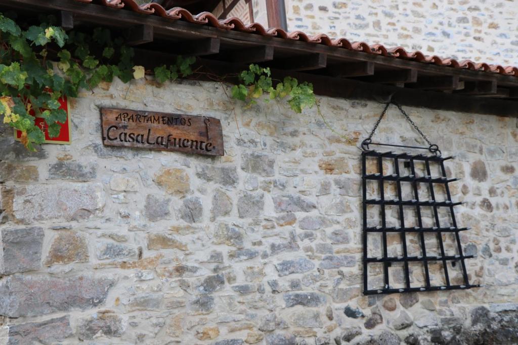 LuquianoApartamentos Rurales Casa Lafuente的石墙边的铁栅栏标志