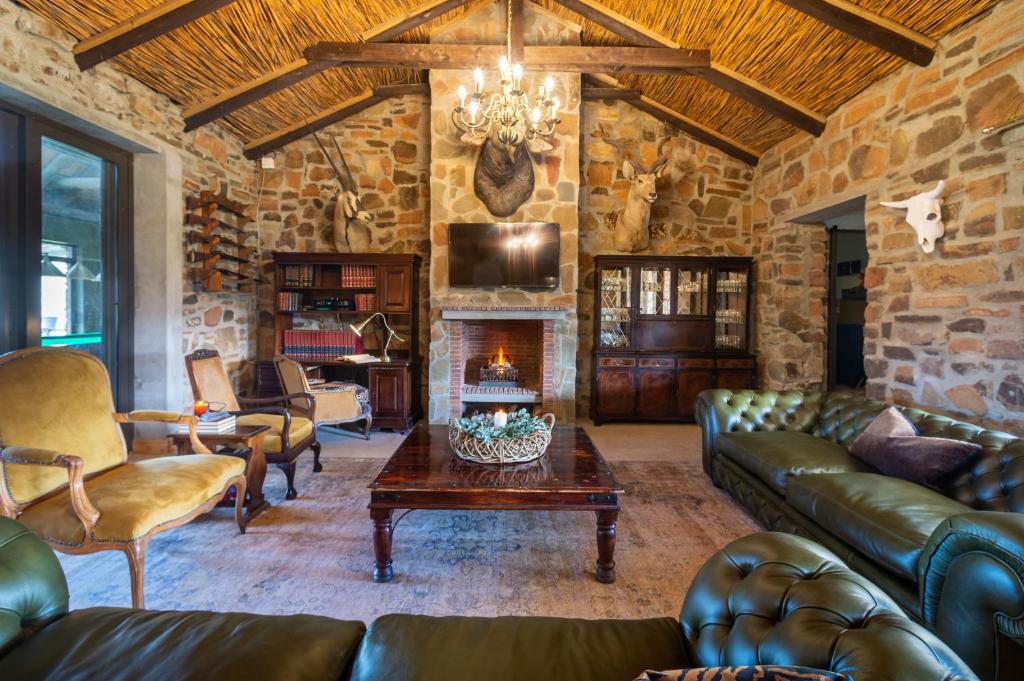 TouwsrivierKamagu Safari Lodge的客厅配有皮革家具和石墙