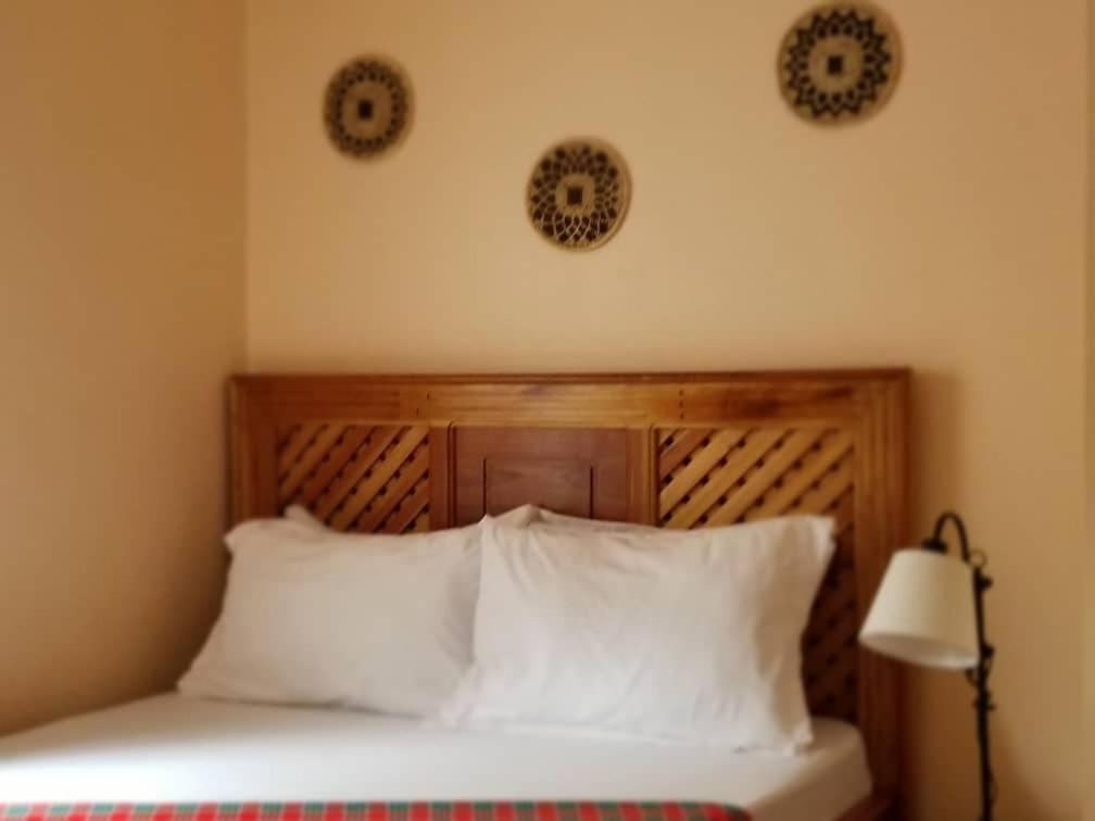 阿鲁沙Maasai Hostel Tanzania的一张带木制床头板和白色枕头的床