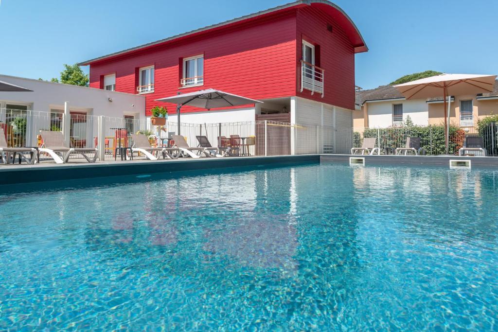 南特南特-贝奥约泽尼图德公寓式酒店的一座红色建筑前的游泳池