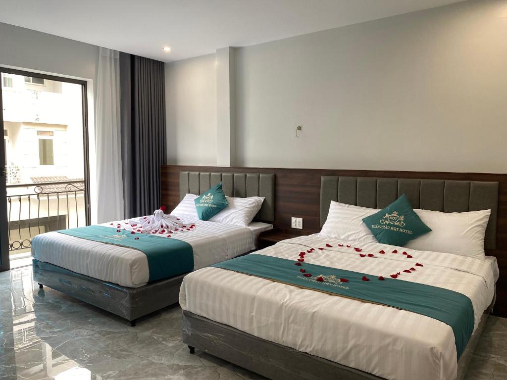 下龙湾Tuần Châu HQT的两张位于酒店客房的床,上面有鲜花