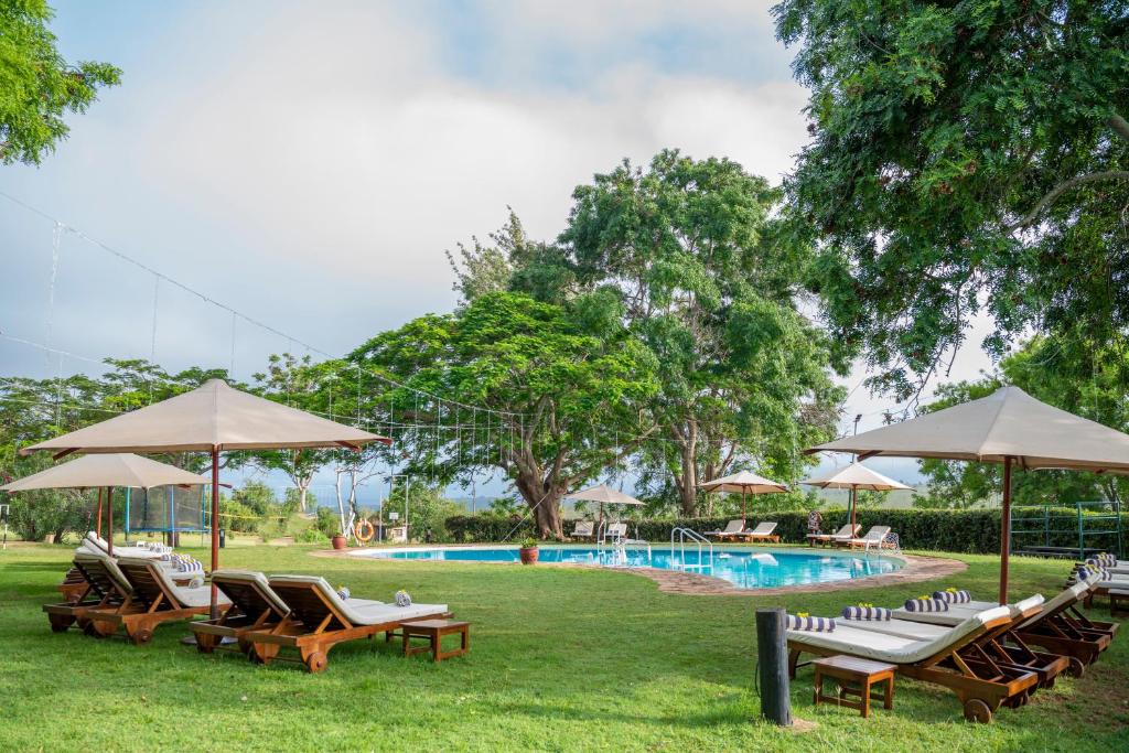 TsavoTaita Hills Safari Resort & Spa的一组椅子和遮阳伞,位于游泳池旁