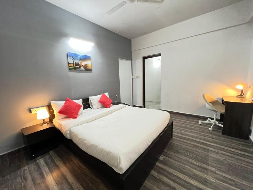 海得拉巴BedChambers Serviced Apartments的一间卧室配有一张带红色枕头的床和一张书桌