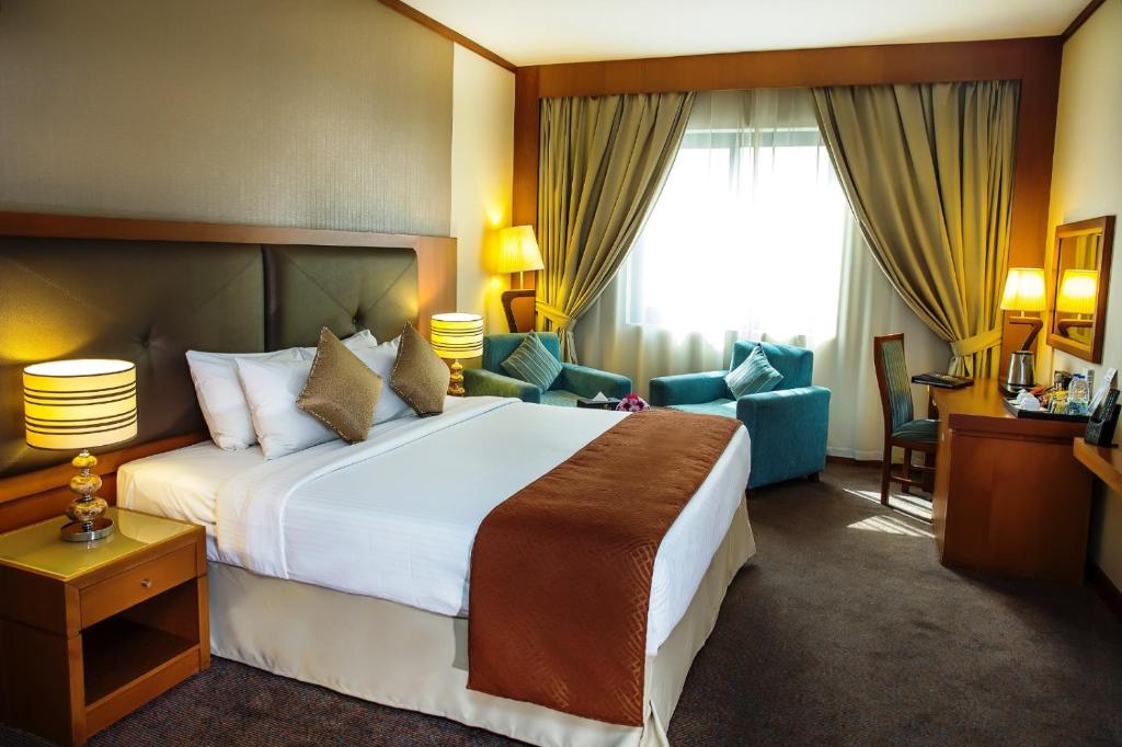 迪拜Landmark Summit Hotel的酒店客房带一张大床和椅子