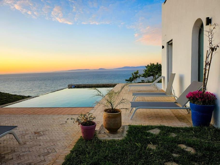 丹吉尔Très belle villa avec piscine et vue incroyable sur mediterannée (DAR NAIM)的坐在房子边的一组长椅