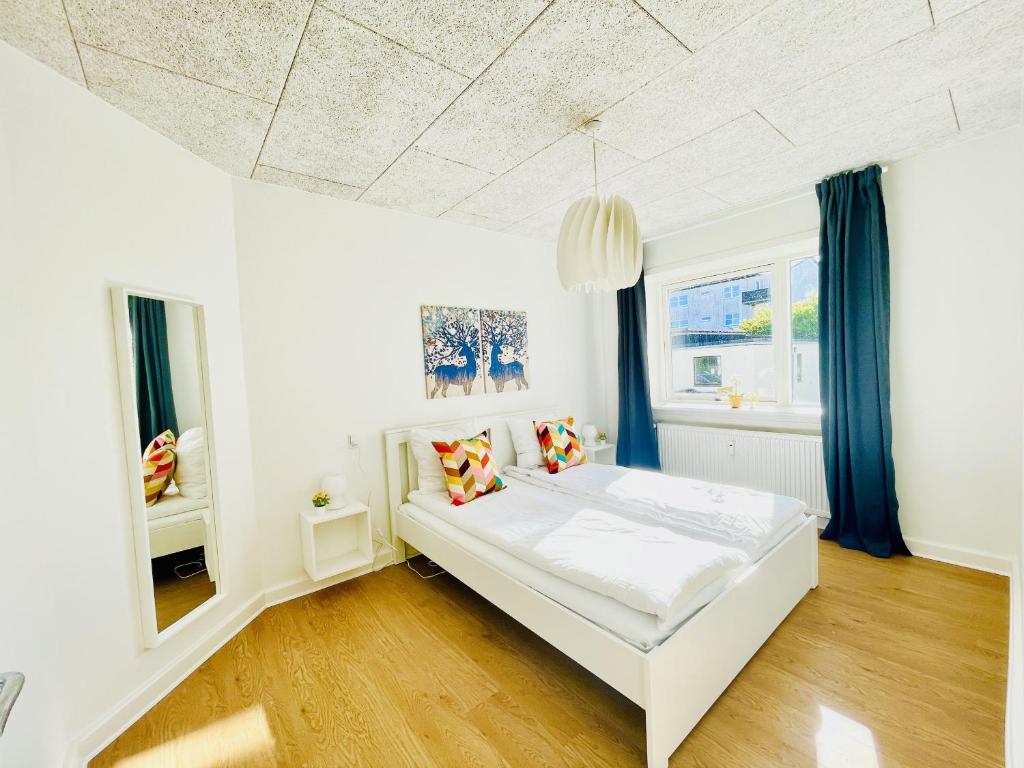 腓特烈港aday - Luminous apartment with 2 bedrooms的卧室配有白色的床和蓝色窗帘